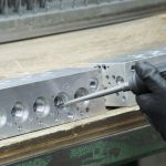 Entgrater, der die Bohrungen in einem Steuerblock von Spänen befreit – Fertigung nach Kundenzeichnung.